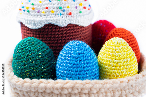 Fashionable color bright knitted eggs, green, blue, yellow, red happy Easter with cupcake in basket, isolated on a white background, close up, macro
