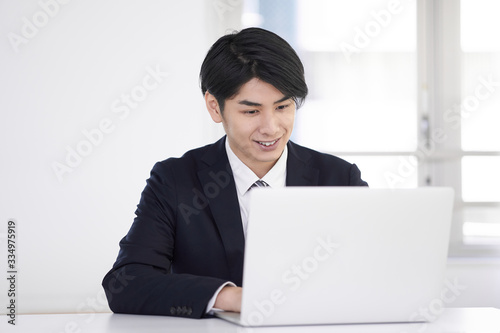 笑顔で自宅でスーツを着てテレワークをする日本人男性ビジネスマン