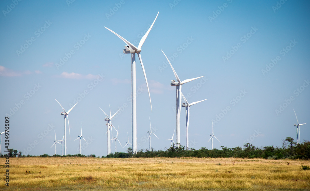 Wind turbines and agricultural field on a summer day. Energy production, clean and renewable energy. Wind turbines and agricultural field on a summer day. Energy production, clean and renewable energy.