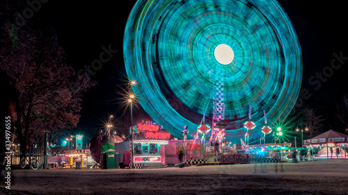 long exposure photograph of ferris wheel with aquamarine lights at night parties