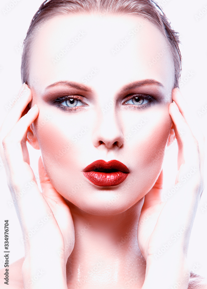 Beautiful face of model woman, perfect skin, bright makeup eye shadows, cherry lips make-up, blue eyes, hands near face Beautiful face of model woman, perfect skin, bright makeup eye shadows, cherry lips make-up, blue eyes, hands near face