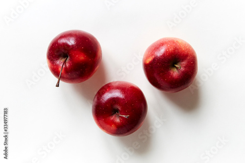 three red apples on white background top view