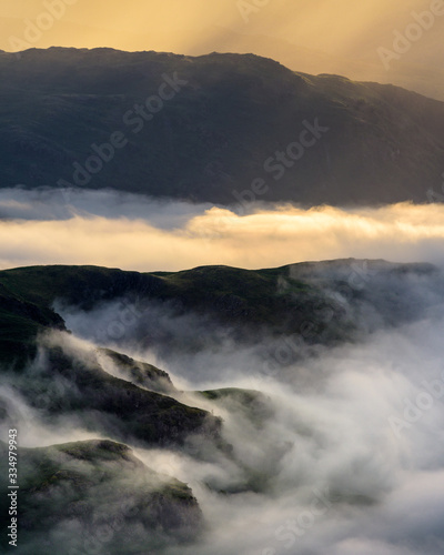 Lake District Mountains Covered In Mist With Rays Of Morning Light.