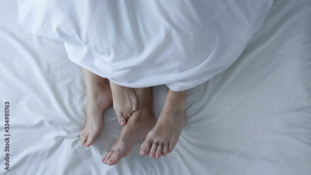 Male and female legs in bed. Couple in bed making petting and love. Romantic couple relaxing together touching legs. Top view. Marriage, family, love, sex concept.