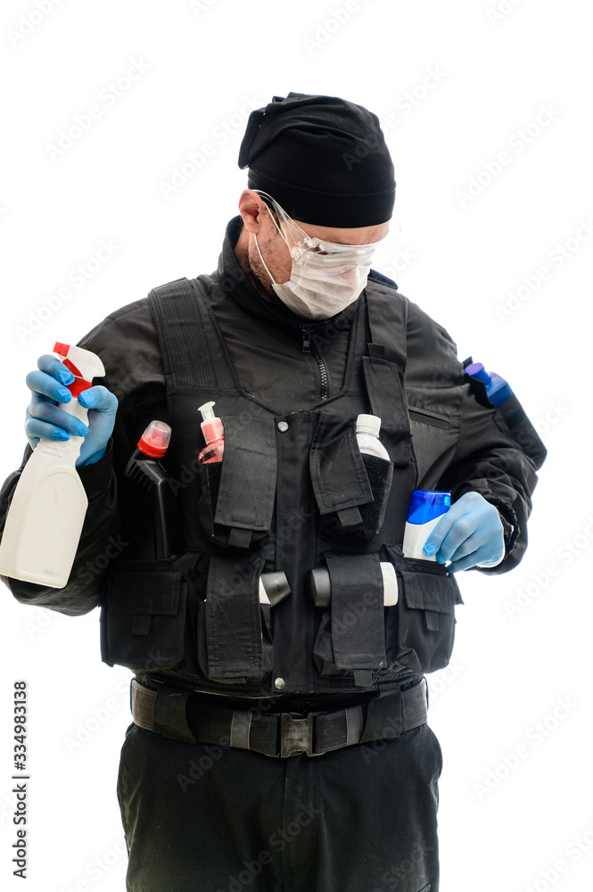 Isolated portrait on white background man in a black military uniform in a medical mask with cleaning products in his hands Isolated portrait on white background man in a black military uniform in a medical mask with cleaning products in his hands