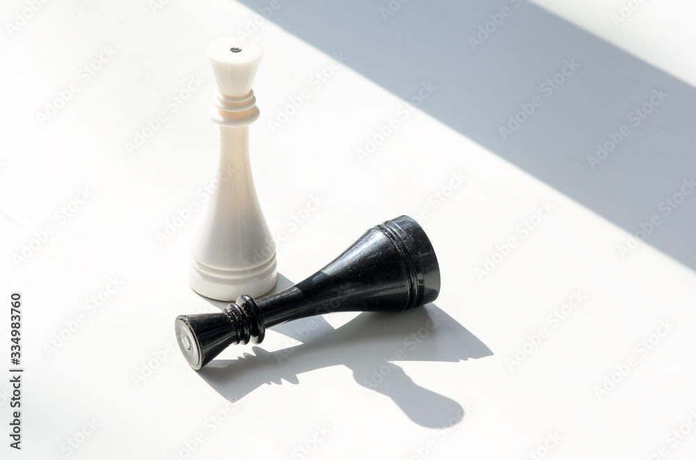 On a white background is a white chess piece. Nearby lies a black chess piece. Concept - win, give up On a white background is a white chess piece. Nearby lies a black chess piece. Concept - win, give up