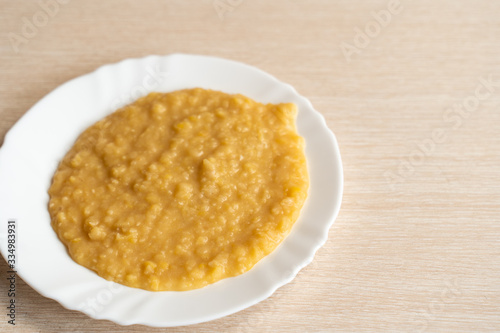 Yellow pea puree in a white plate © EvgenII