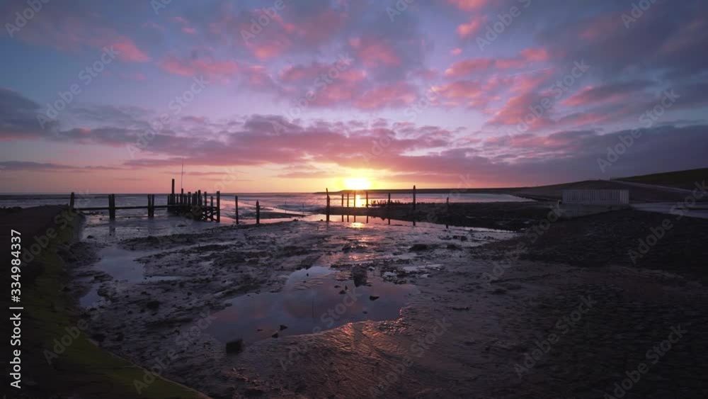 Magical sunset at Texel Island. Colorful red and purple clouds over wet beach mudflats and sea at Wadden Island Texel, Netherlands