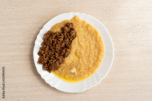Yellow pea puree with meat in a white plate
