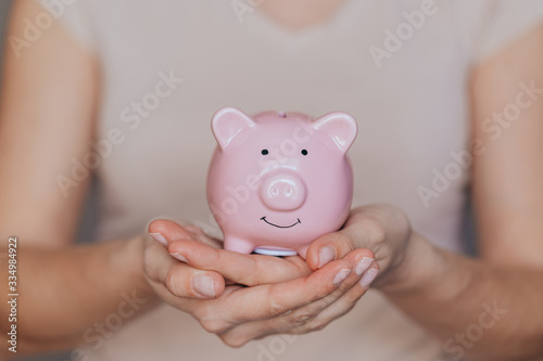 female hands protect pink piggy bank, copy space. Concept of saving money or savings