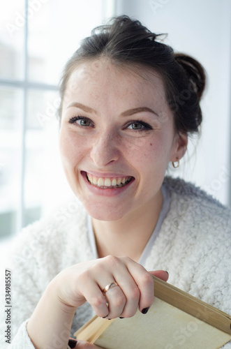 photo of a young beautiful smiling girl with a book