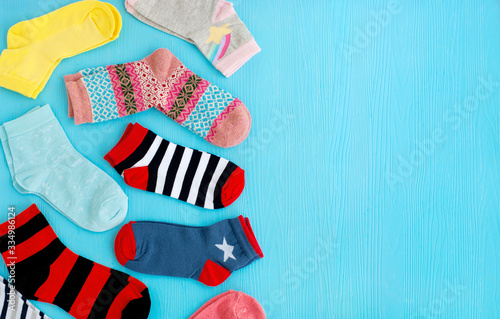 Colorful socks on a blue background. Socks of different sizes and colors for the cold seasons. Clothing for autumn and winter. Lots of socks and space for text.