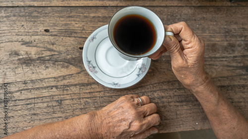 hand holding a black coffee on wooden table. ceramic round cup.