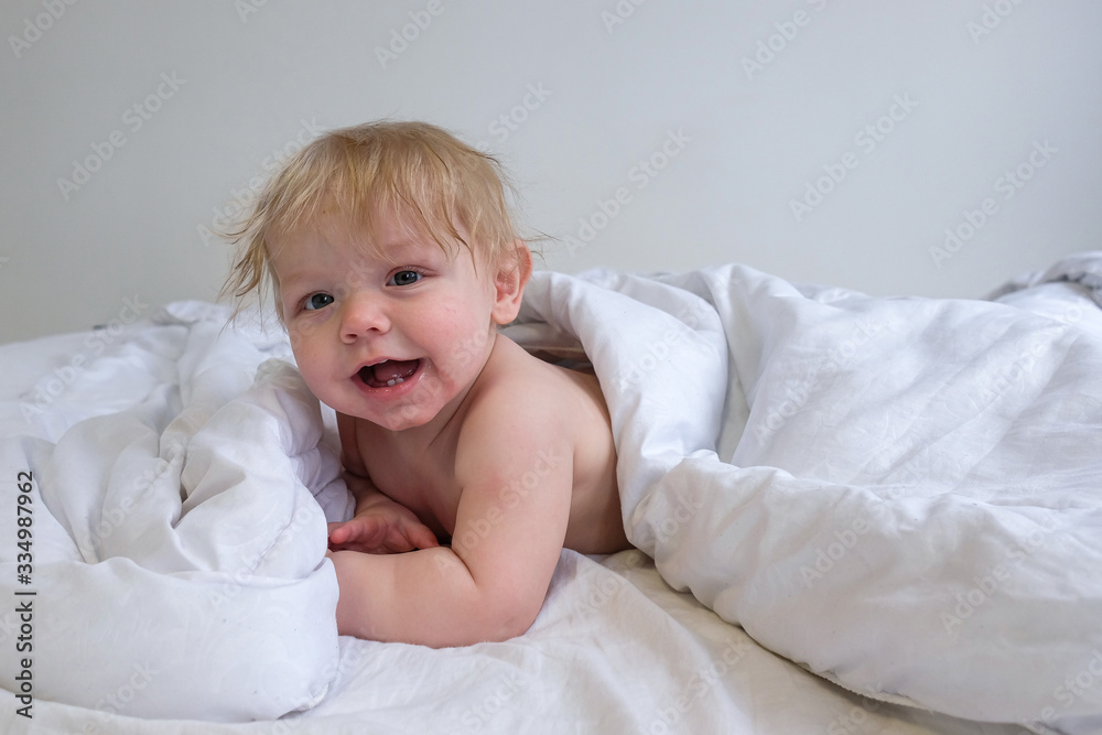 little boy with snot at home in a white bed, an infant is happy and resting in bed