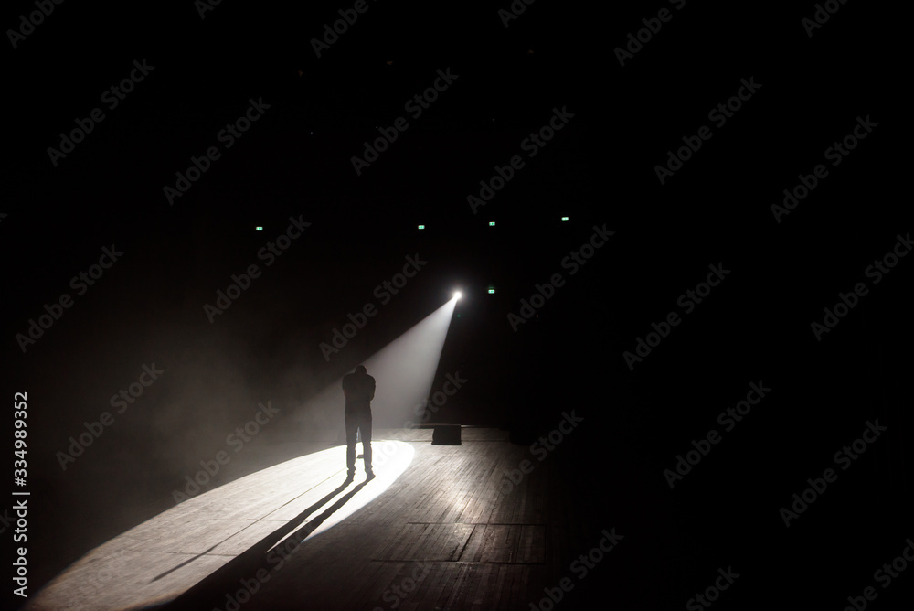Stand up comedian on stage in the beam of light. - obrazy, fototapety, plakaty 