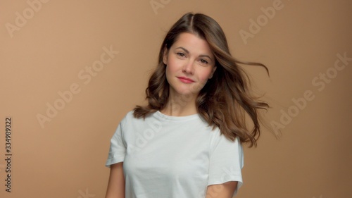 Monochrome natural makeup look Caucasian woman in studio in white t-shirtwith healthy shiny hair blowing