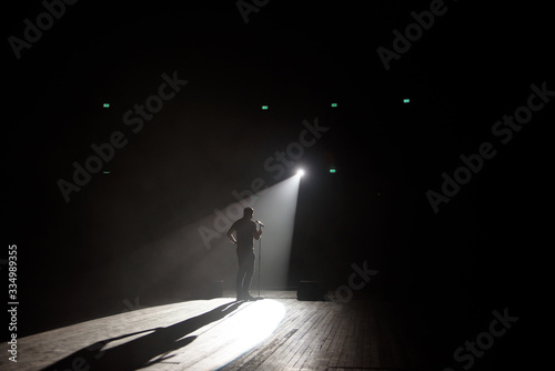 Stand up comedian on stage in the beam of light.