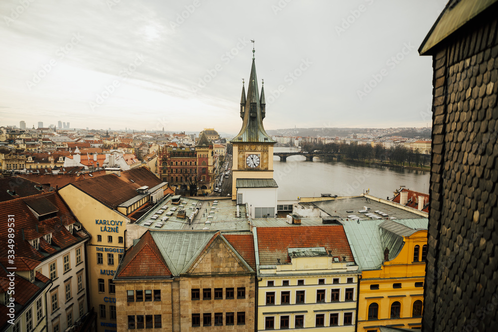 Naklejka premium Close up view to old Town Bridge Tower, clock tower and St. Francis Of Assisi Church in Prague, Czech Republic while sunset. 
