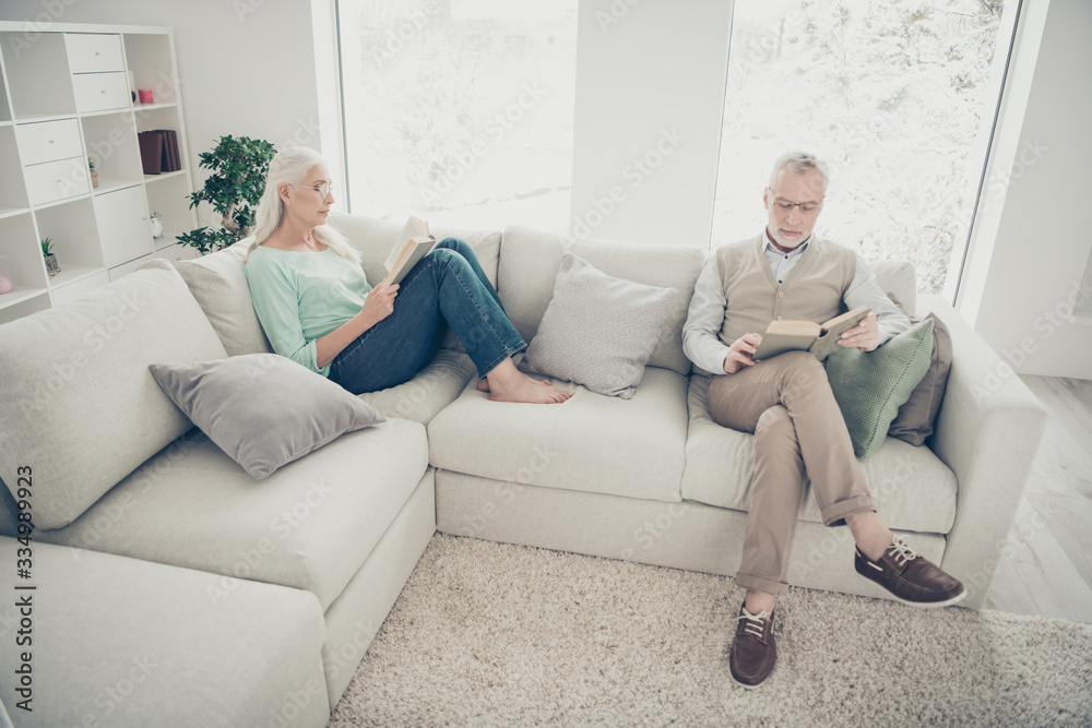 Photo of white haired aged pair curious reading adventure stories comfy sitting sofa indoors Photo of white haired aged pair curious reading adventure stories comfy sitting sofa indoors
