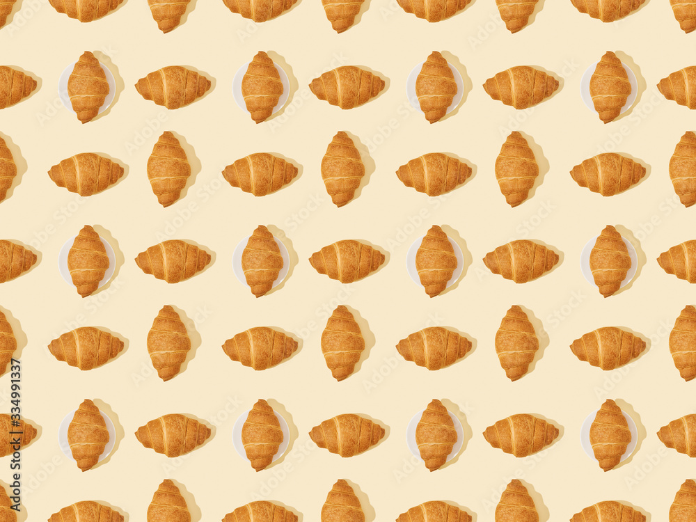 top view of fresh croissants on beige, seamless background pattern top view of fresh croissants on beige, seamless background pattern