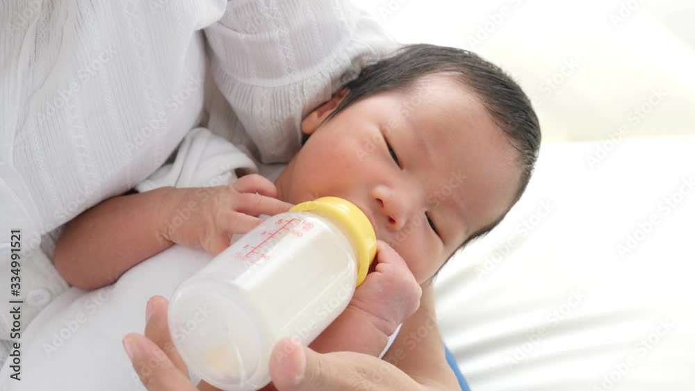 Little asian baby drinking milk from mother feeding him by bottle milk.