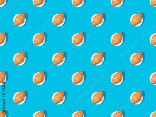 top view of fresh croissants on plates on blue, seamless background pattern