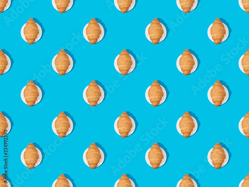 top view of fresh croissants on plates on blue, seamless background pattern