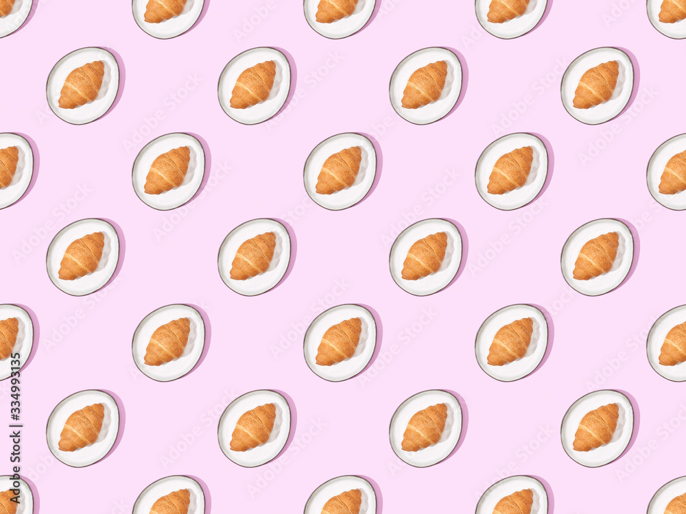 top view of croissants on plates on pink, seamless background pattern top view of croissants on plates on pink, seamless background pattern