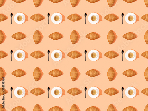 top view of spoons, fresh croissants on plates and coffee on orange, seamless background pattern