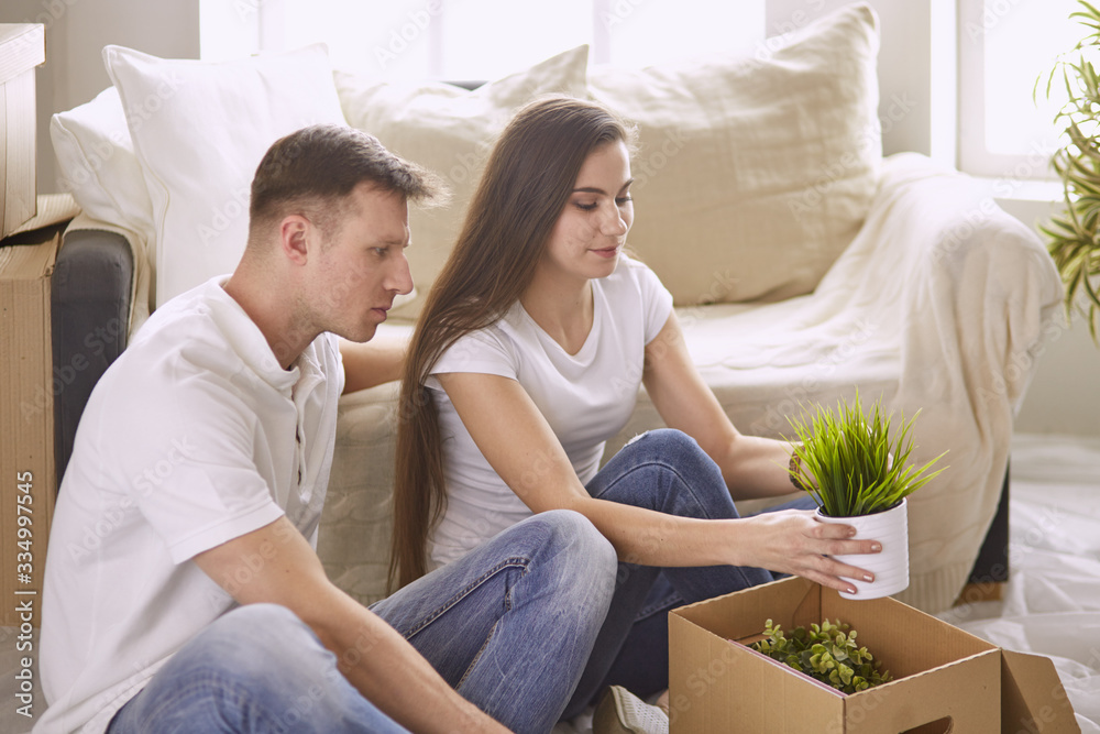 Portrait of happy couple looking at laptop computer together sitting in new house, surrounded with boxes Portrait of happy couple looking at laptop computer together sitting in new house, surrounded with boxes