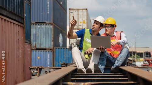industrial background of caucasian containers yard and cargo loading controller and asian inspector working together on container truck at containers loading area outdoors © Mongkolchon