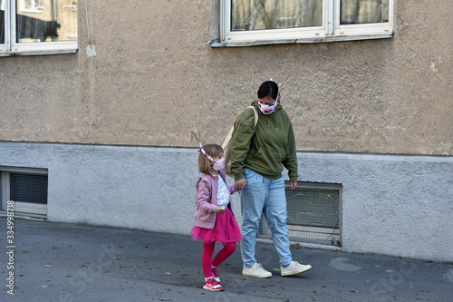 Daughter and mom wearing diy face masks for protetion against coronavirus, walking in the street. photo