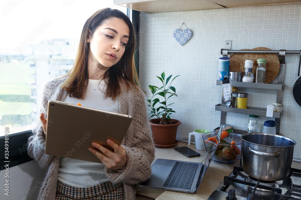 ragazza vestita comoda casual in cucina mentre guarda il suo tablet mentre cucina ragazza vestita comoda casual in cucina mentre guarda il suo tablet mentre cucina