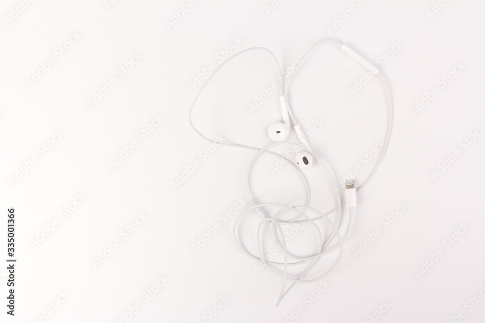 Fototapeta White headphones for listening to music and sound on portable devices: music player, smartphone, laptop and jack for connection on a white background.