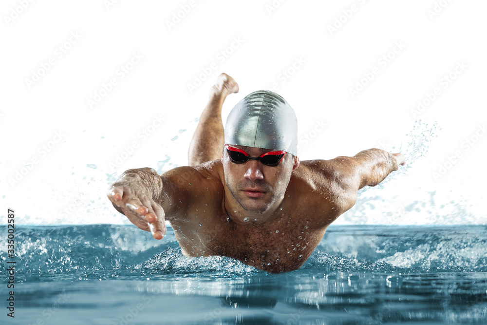 Professional caucasian male swimmer with hat and goggles practicing and training isolated on white background and pool. Grace of motion and action. Healthy lifestyle, sport and movement concept.