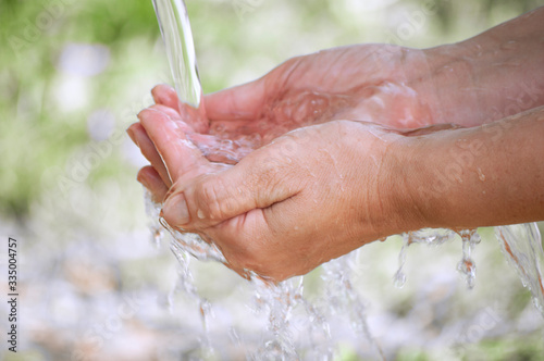 a person collects clean water in his hands, which flows in a stream