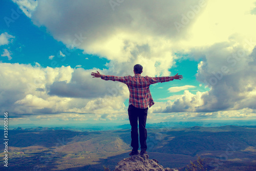 A man stand on the top mountain cliff and acting of freedom life style travel trip successful background textures concept.