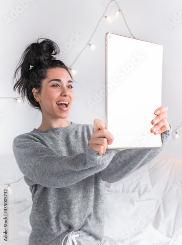 beautiful girl in comfortable clothing on white duvet photo