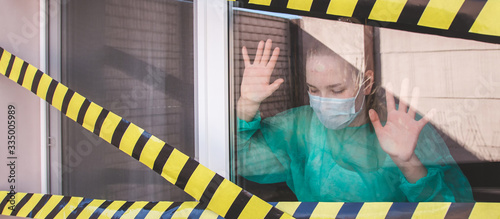 coronavirus covid 19 quarantine warning tape window of the quarantine room in the hospital with coronavirus cvid19, concept of quarantine of the coronavirus pandemic. Girl in a mask behind a glass photo