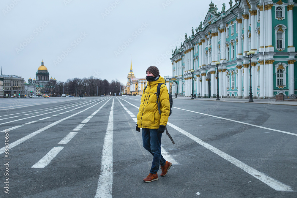 Young man in yellow jacket walking on the road. Empty dvortsovaya square in the centre on self isolation