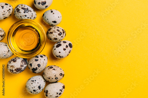 Fototapeta Quail eggs with olive oil on a yellow background with place for text, top view