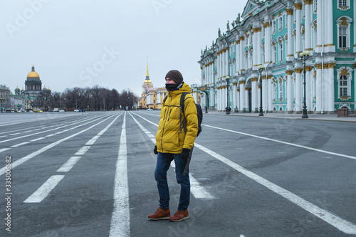 Young man in yellow jacket walking on the road. Empty dvortsovaya square in the centre on self isolation photo