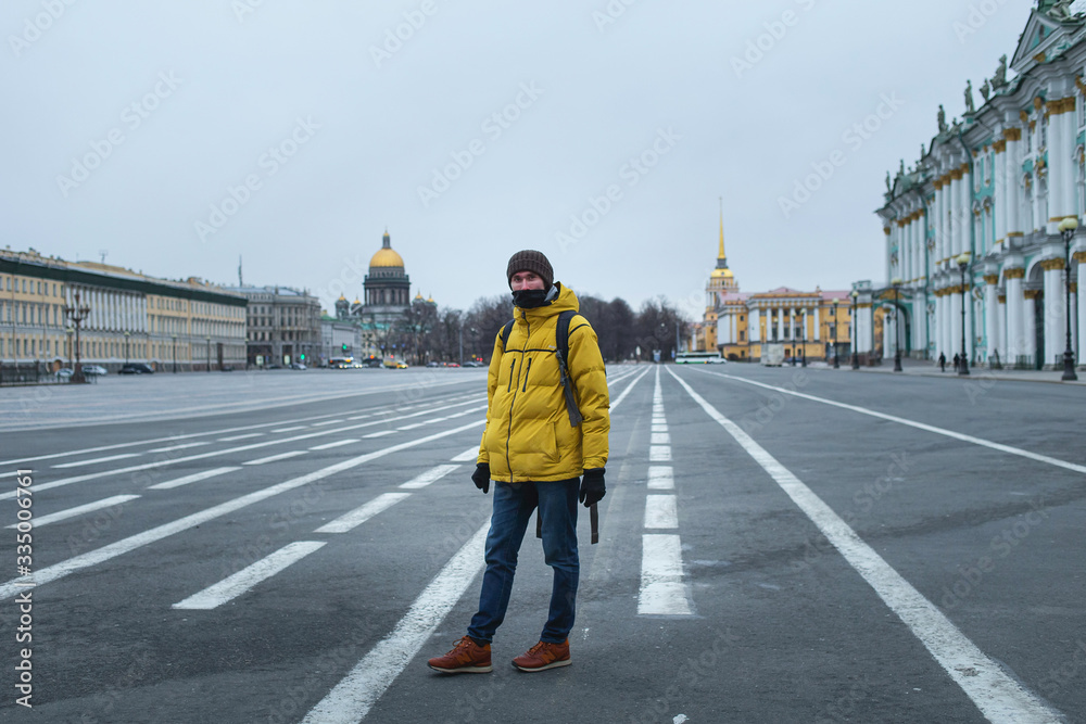 Young man in yellow jacket walking on the road. Empty dvortsovaya square in the centre on self isolation