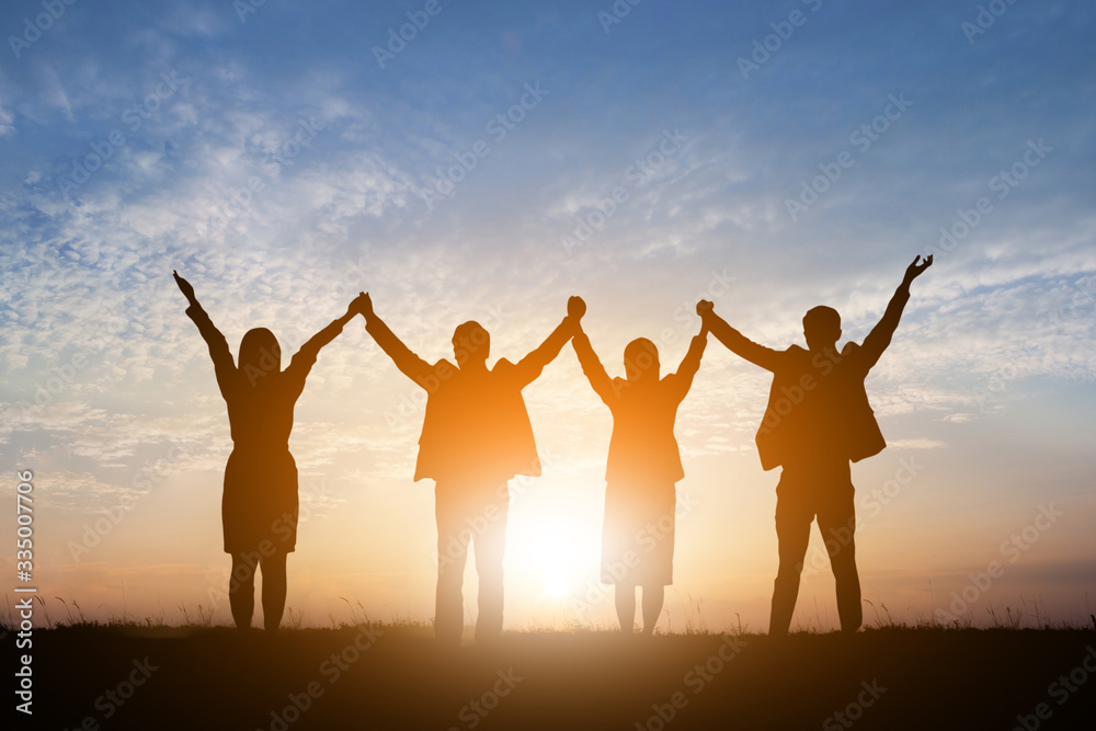 Silhouette of happy business teamwork making high hands over head in sunset sky background for business teamwork concept Silhouette of happy business teamwork making high hands over head in sunset sky background for business teamwork concept