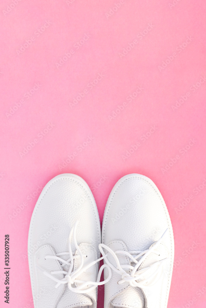 white sneakers on a pink background. view from above. copyspace. place for text. vertical photo