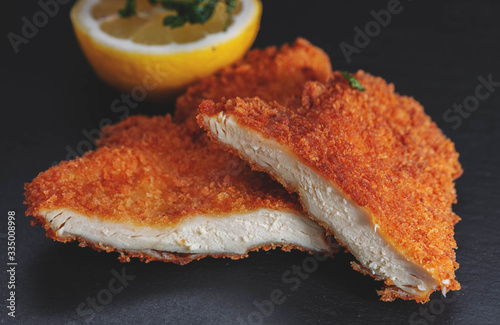 Canvas Print original Wiener Schnitzel, goldgelb gebacken, frisch und knusprig mit Zitrone und frittierter Petersilie dekoriert