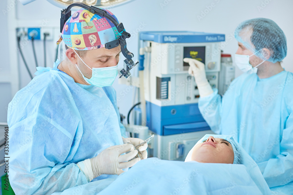 Several doctors surrounding patient on operation table during their work. Team surgeons at work in operating room Several doctors surrounding patient on operation table during their work. Team surgeons at work in operating room