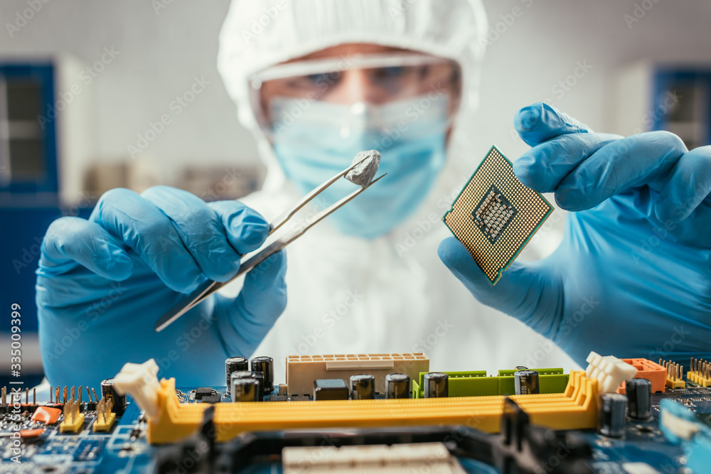 selective focus of engineer holding small stone with tweezers and microchip near computer motherboard