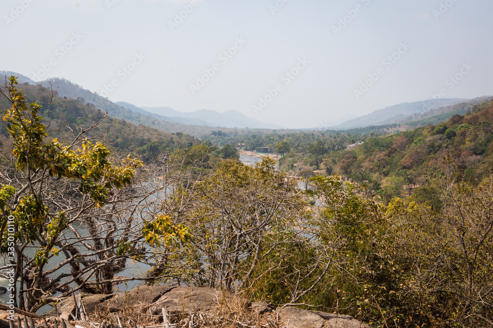 A huge waterfall Athirapally in Kerala, India. White streams of water of the waterfall break into small splashes and flow in a strong stream, Indian tourists look at the attraction