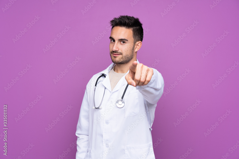 Young man wearing a doctor gown and pointing to the front Young man wearing a doctor gown and pointing to the front